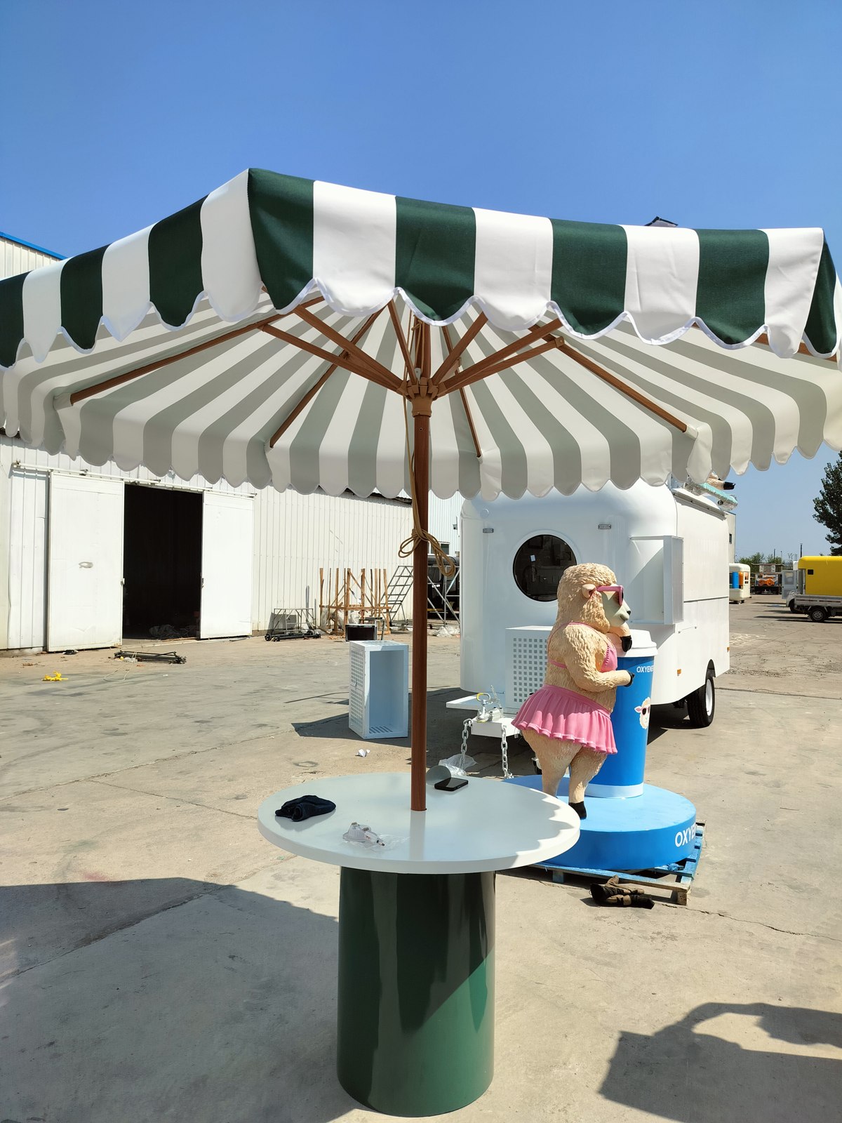 Round table, shade equipment and brand sculpture arranged together