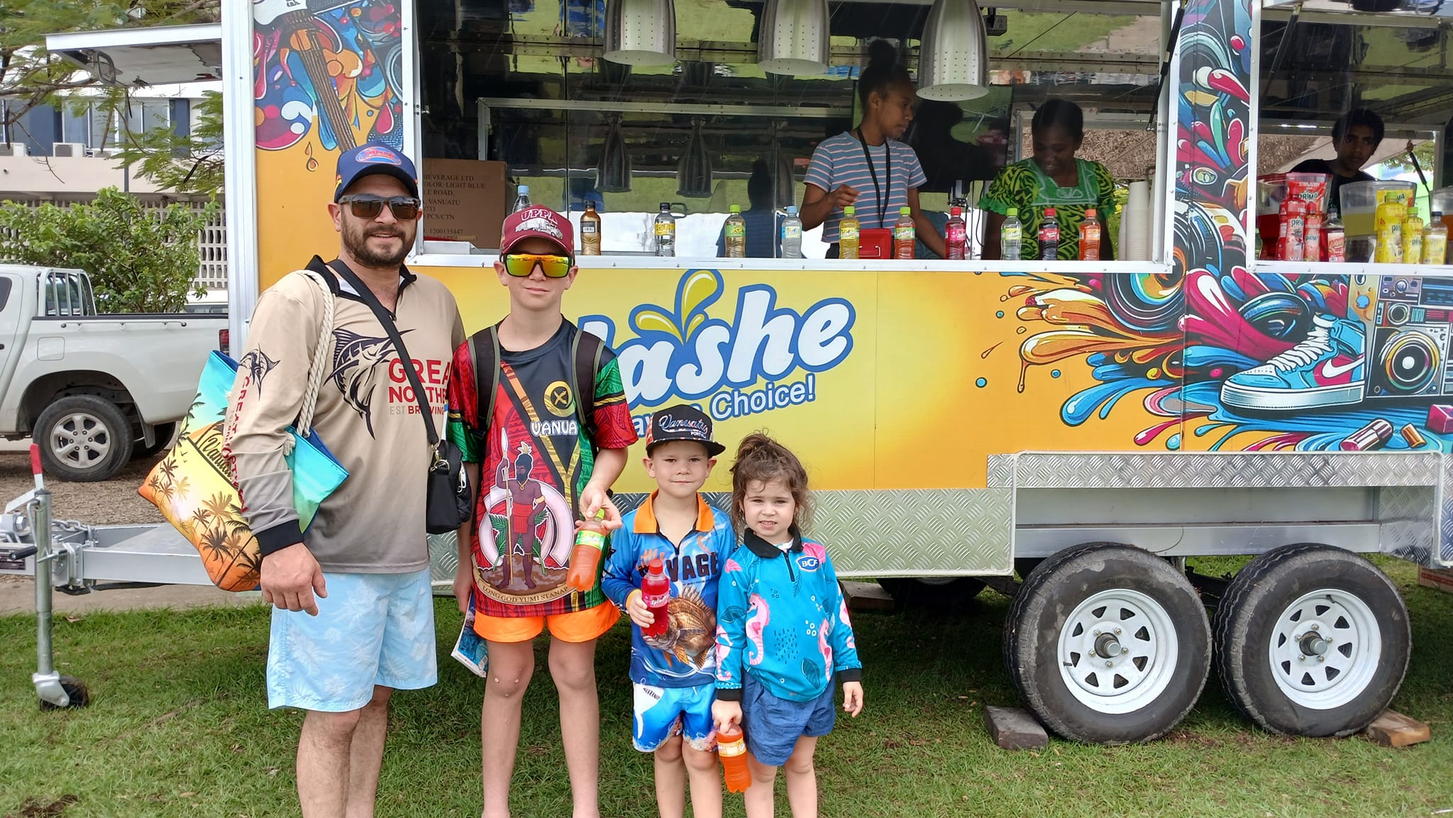 Customers standing beside a colorful drinks trailer in service
