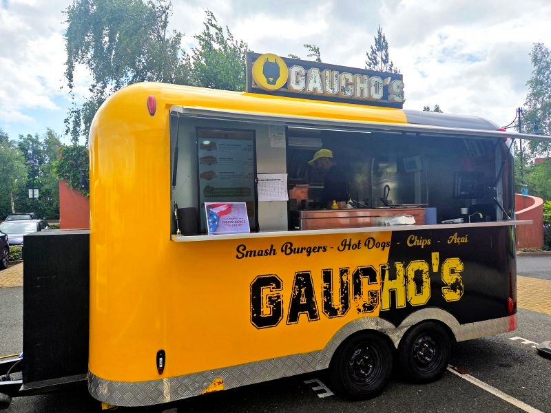 Yellow and black Gaucho's burger trailer operating at a customer location