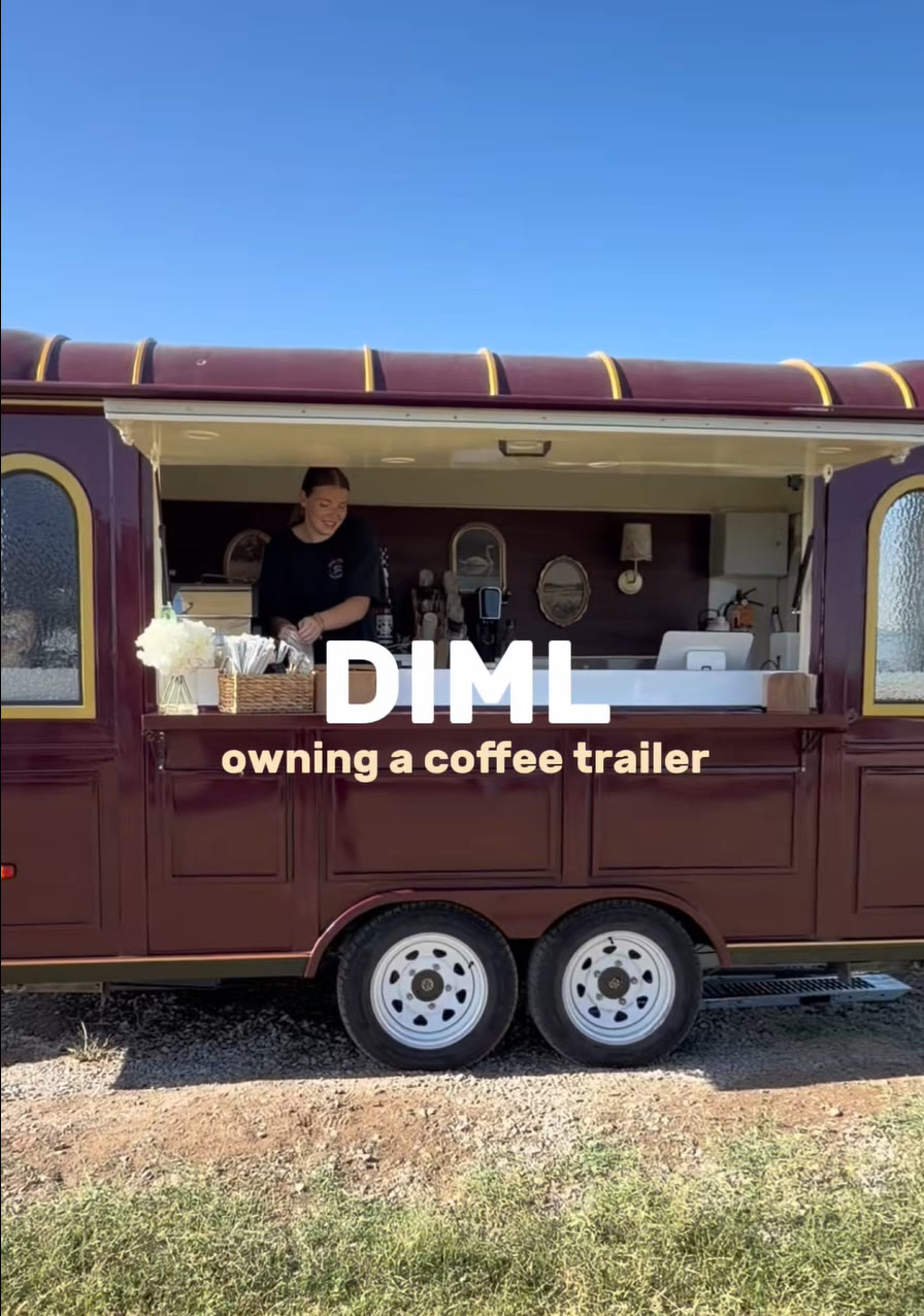 Owner working inside the open serving window of the burgundy coffee trailer